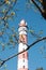 Red and white lighthouse on the background of a blue sky and branches