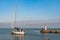 Red and white lighthouse with people and sailboat