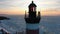 Red and white lighthouse stands on island against frozen sea