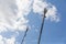 Red and white mobile phone cell tower repeater, with a small microwave dish on blue sky with clouds background