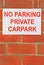 Red and white No Parking Private Carpark sign on brick wall