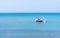 Red and white pedalo on a calm blue sea, near yellow buoys