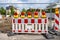 Red and white plastic portable barrier in front of a construction site. Red signal lights