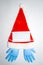 Red and white plush Christmas Santa hat with surgical mask and one pair of inflated blue medical vinyl gloves. Top view.