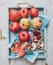 Red and white pomegranates with knife on kitchen towel in blue tray over light painted wooden backdrop