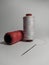 red and white sewing thread spool and needle