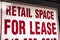 A red and white sign saying retail space for lease with border hangs in a vacant storefront glass window in Chicago during the