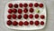 Red and white strawberries lie on a white plate. The light moves counterclockwise in a circle. Concept - Stand out from the crowd