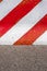 Red and white striped concrete road barrier on asphalt.