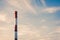 Red and white striped plant pipe at sunset against blue sky with copy space