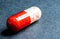 Red-white tablet capsule with red-white balls on black background