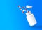 Red-white tablets explode from a flying bottle on blue background with copy space
