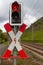 Red and white traffic sign for railroad crossing with a red stoplight