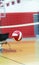 Red and white volleyball in front of net