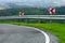 Red and white warning signs before a dangerous road bend in a mountainous area