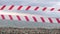 Red white warning tape barrier ribbon swinging in the wind across exotic sea beach background without people. No entry