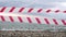 Red white warning tape barrier ribbon swinging in the wind across exotic sea beach background without people. No entry