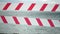 Red white warning tape barrier ribbon swinging in the wind across exotic sea beach background without people. No entry