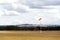 Red and white windsock on empty grassy airfield, dramatic clouds in background, windy weather forecast and air traffic