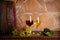 Red and white wine with grapes beside old cask in wine cellar. Glasses and bottles of wine on wooden table.