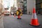 Red and white witches hat cone traffic warning sign barrier applying on busy street downtown on pedestrian footpath