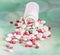 Red, white, yellow drugs pills with white open plastic bottle, p