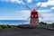 Red windmill on Pico coastline with blue clear sky in Azores