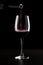 Red wine being poured into a glass and splashing over the side. Low key black background