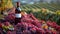 A red wine bottle in front of a landscape of grape farmland.