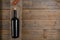 Red wine bottle with stopper, corkscrew and grapes leaves on natural wooden table background