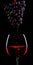 Red wine flow from a cluster of grapes to the glass of wine.Black background.Red wine.Advertising shot