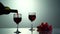 Red wine forms beautiful wave. Wine pouring in wine glass over black background. Close-up shot. Slow motion of pouring
