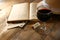 Red wine glass and old book on wooden table at sunset burst. vintage filtered image