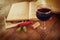 Red wine glass and old book on wooden table at sunset burst. vintage filtered image