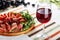 Red wine glass with sliced jamon plate on table background. Horizontal close-up view