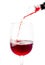 Red wine is poured through aerator into a glass with a thin stream. White background. Isolated. Close-up