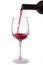 Red wine is poured into a glass from a bottle, isolate on a white background,