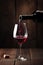 Red wine pouring into glass on black background, created using generative ai technology