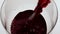 Red wine pouring glass closeup. Beautiful merlot bubbling splashing in goblet
