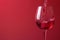 Red wine pouring with splashes on red background closeup. Glass of wine, drink for celebrating, date, family dinner, party. Wine