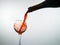 Red wine pouring into a wine glass, white background