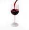 Red wine pours into a tall glass