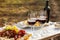 Red wine and snacks served for picnic on wooden table outdoors