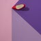 Red women\\\'s high heel on the edge of a purple cube on a pink background. Minimal flat lay composition