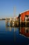 Red wooden boathouse mirrored in reflection in blue water