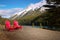 Red wooden chairs on the lakeside with densely forested hills background