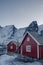 Red wooden cottage on coastline with snowy mountain and the moon in Reine village at Lofoten Islands