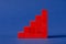 Red wooden cubes assembled in growing column graph over blue background