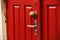 Red wooden door with round ornate handle and traditional handle