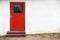 Red wooden door in white rural wall